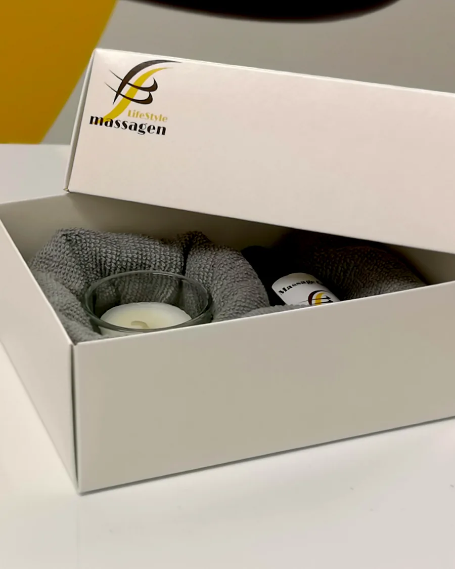 Geöffnete Gutschein-Box von LifeStyle Massagen mit Massageöl, Handtuch und Kerze